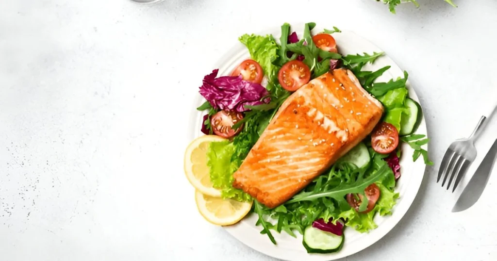 A vibrant salmon bowl featuring grilled salmon, steamed rice, colorful vegetables, and a drizzle of sesame sauce, garnished with sesame seeds and lime wedges.