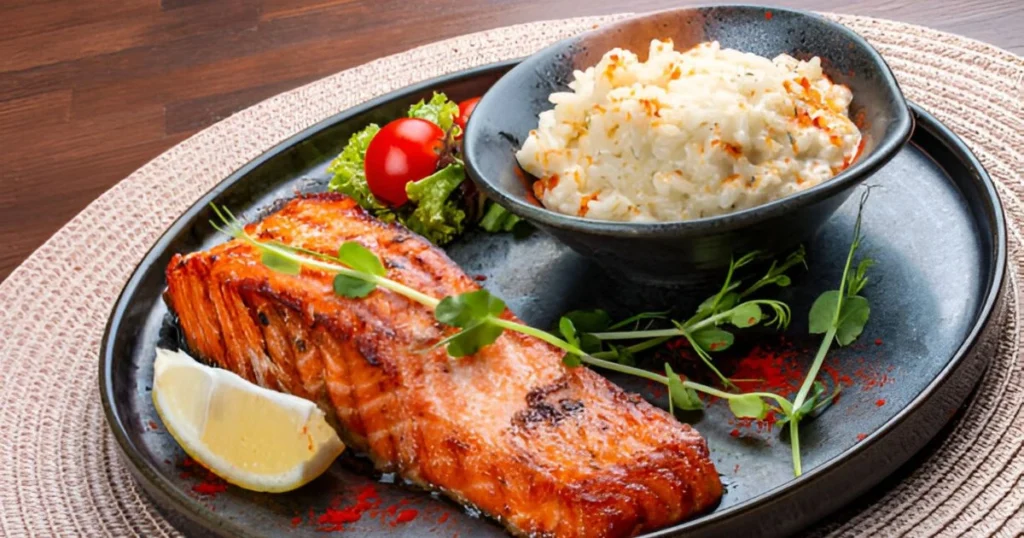 A plate of perfectly cooked salmon fillet served over fluffy rice with a garnish of fresh herbs and lemon slices