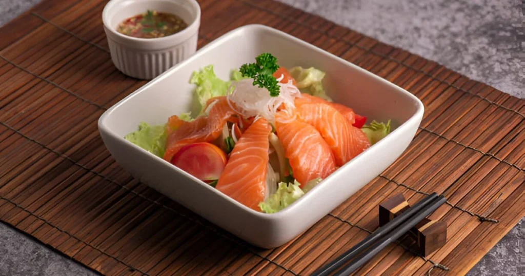 A freshly baked salmon sushi bake served in a casserole dish, garnished with furikake, green onions, and a drizzle of sriracha mayo, ready to be enjoyed with nori sheets.