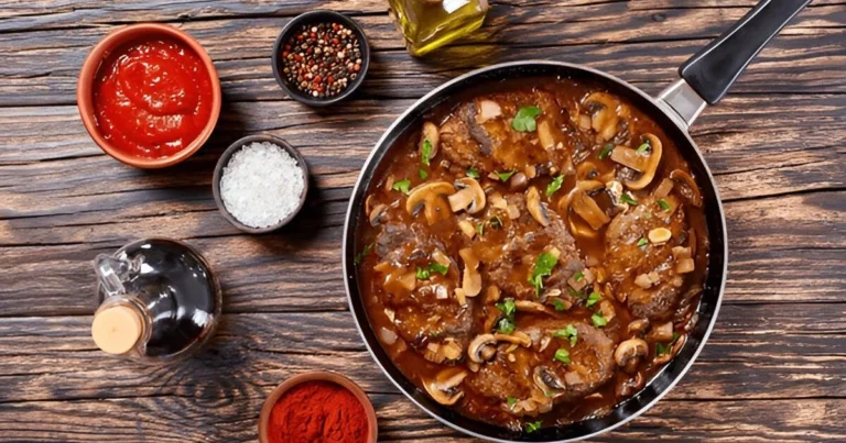 Delicious homemade hamburger steak served with rich brown gravy, garnished with fresh parsley, alongside mashed potatoes and steamed vegetables.